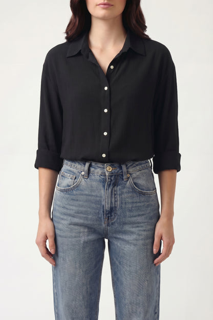 Person wearing a black shirt and blue jeans on a white background