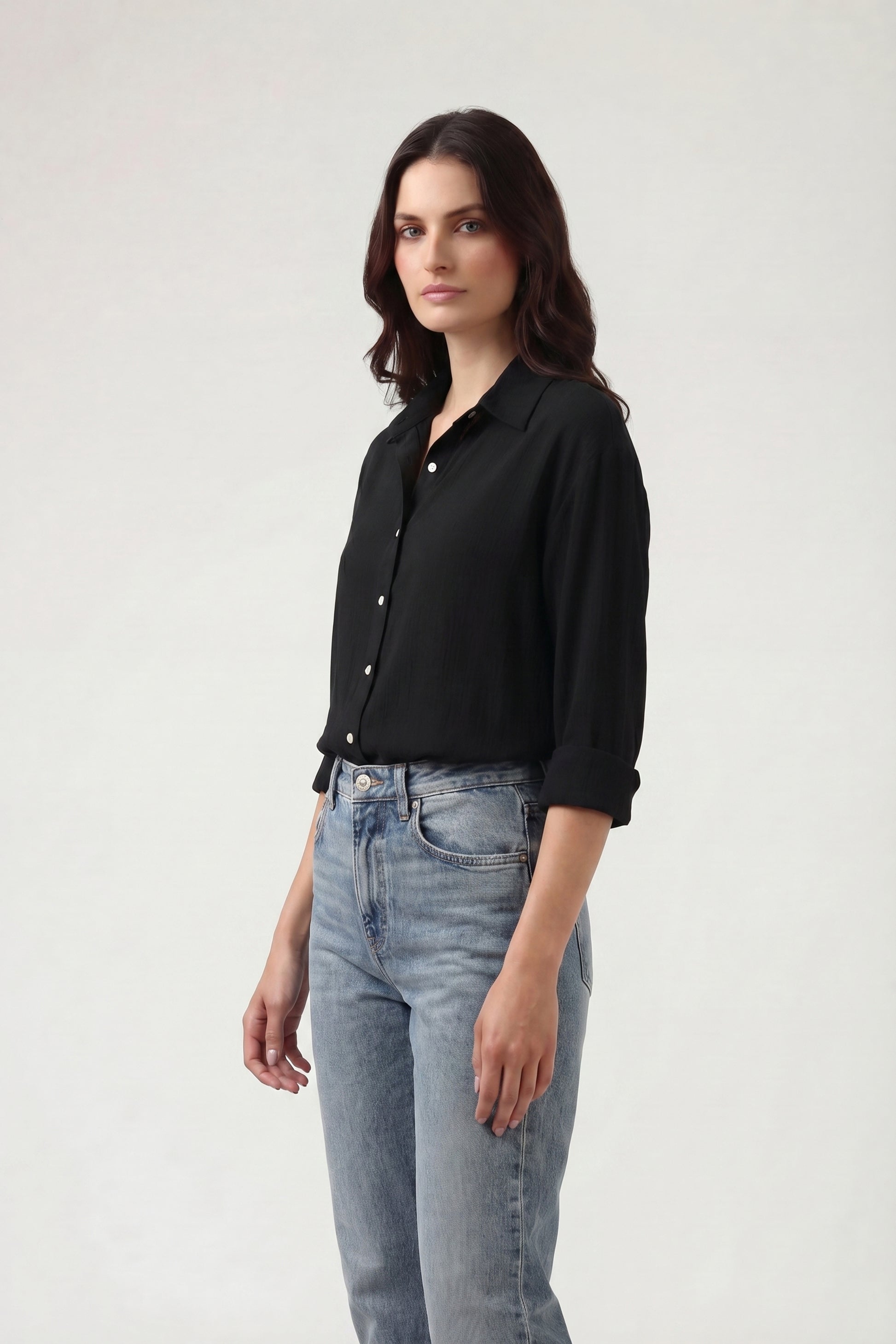 Woman wearing a black shirt and light blue jeans on a white background