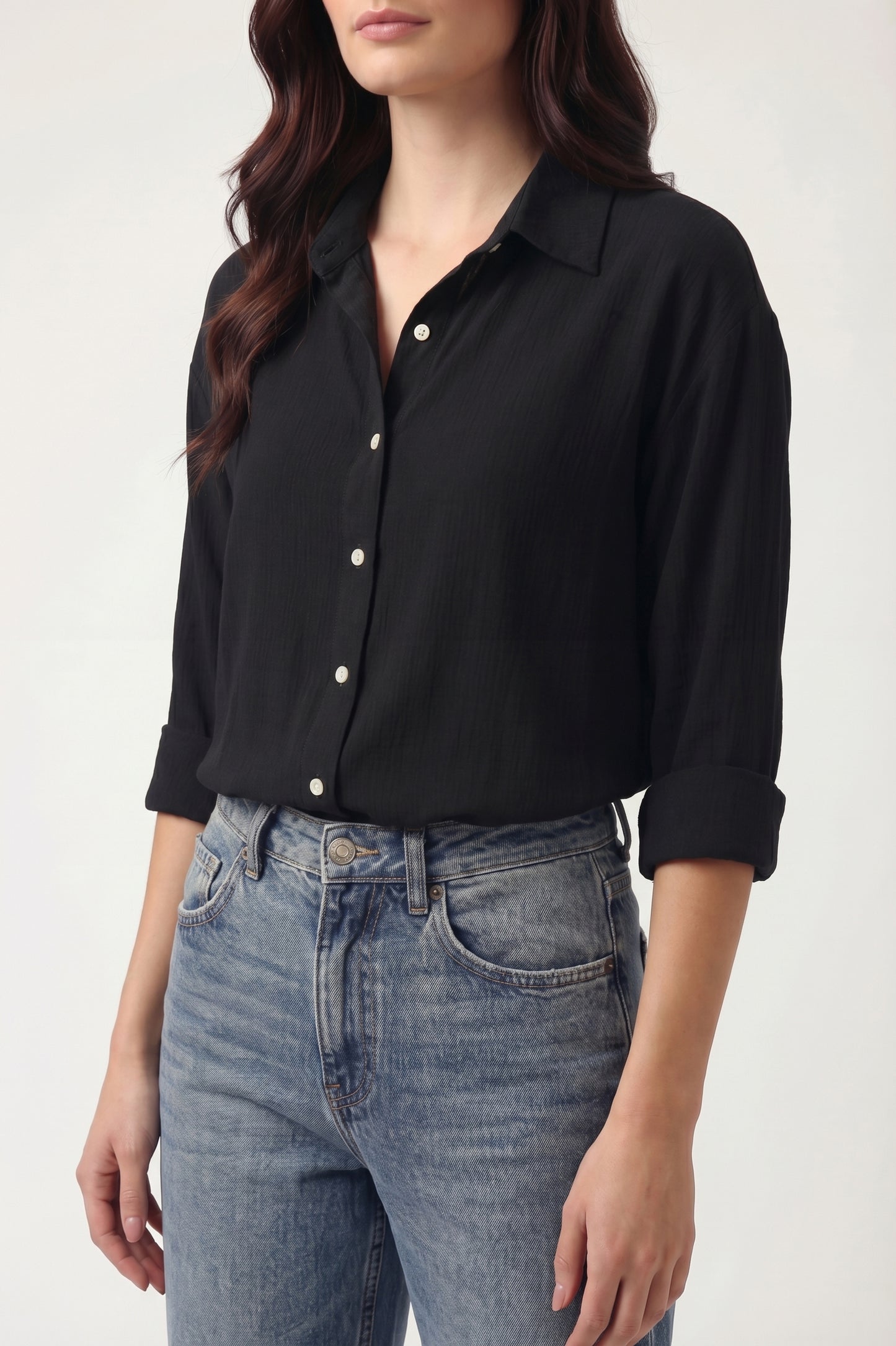 Person wearing a black shirt and blue jeans against a white background
