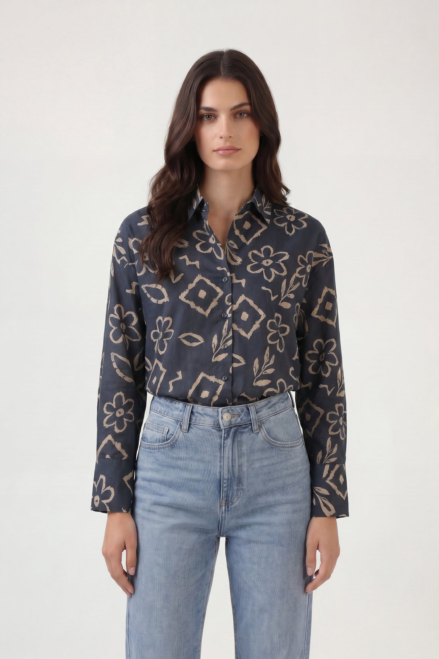 Woman wearing a patterned shirt and jeans on a white background