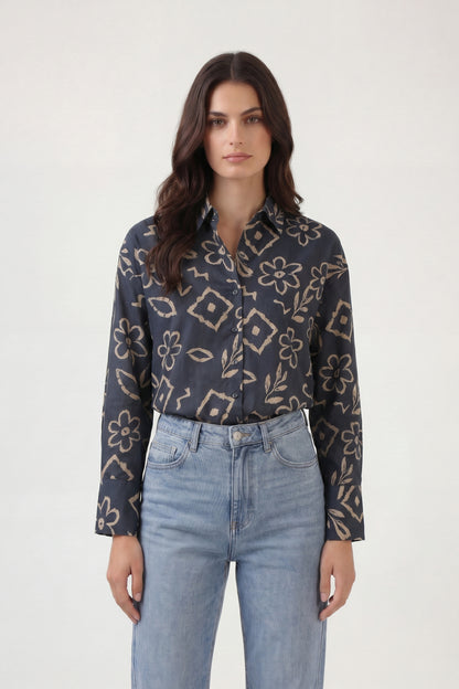 Woman wearing a patterned shirt and jeans on a white background
