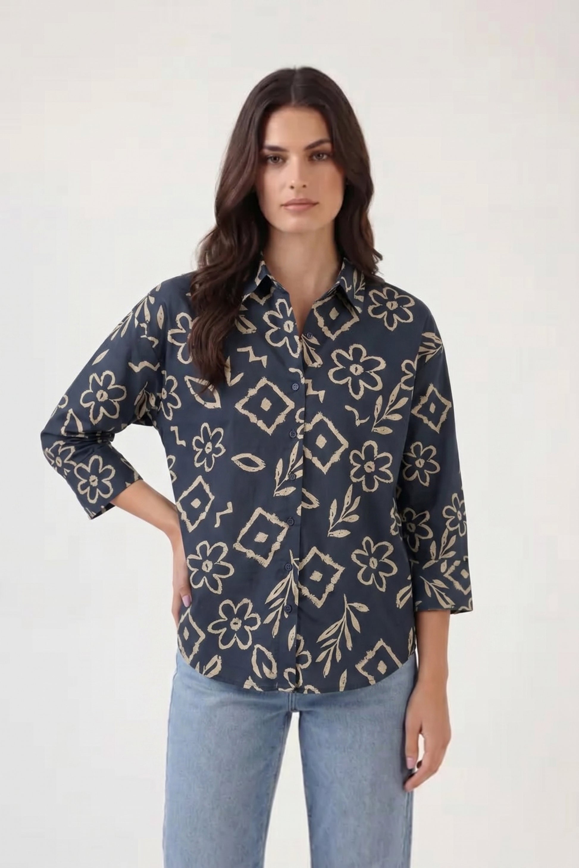Woman wearing a dark blue patterned shirt and light blue jeans on a white background
