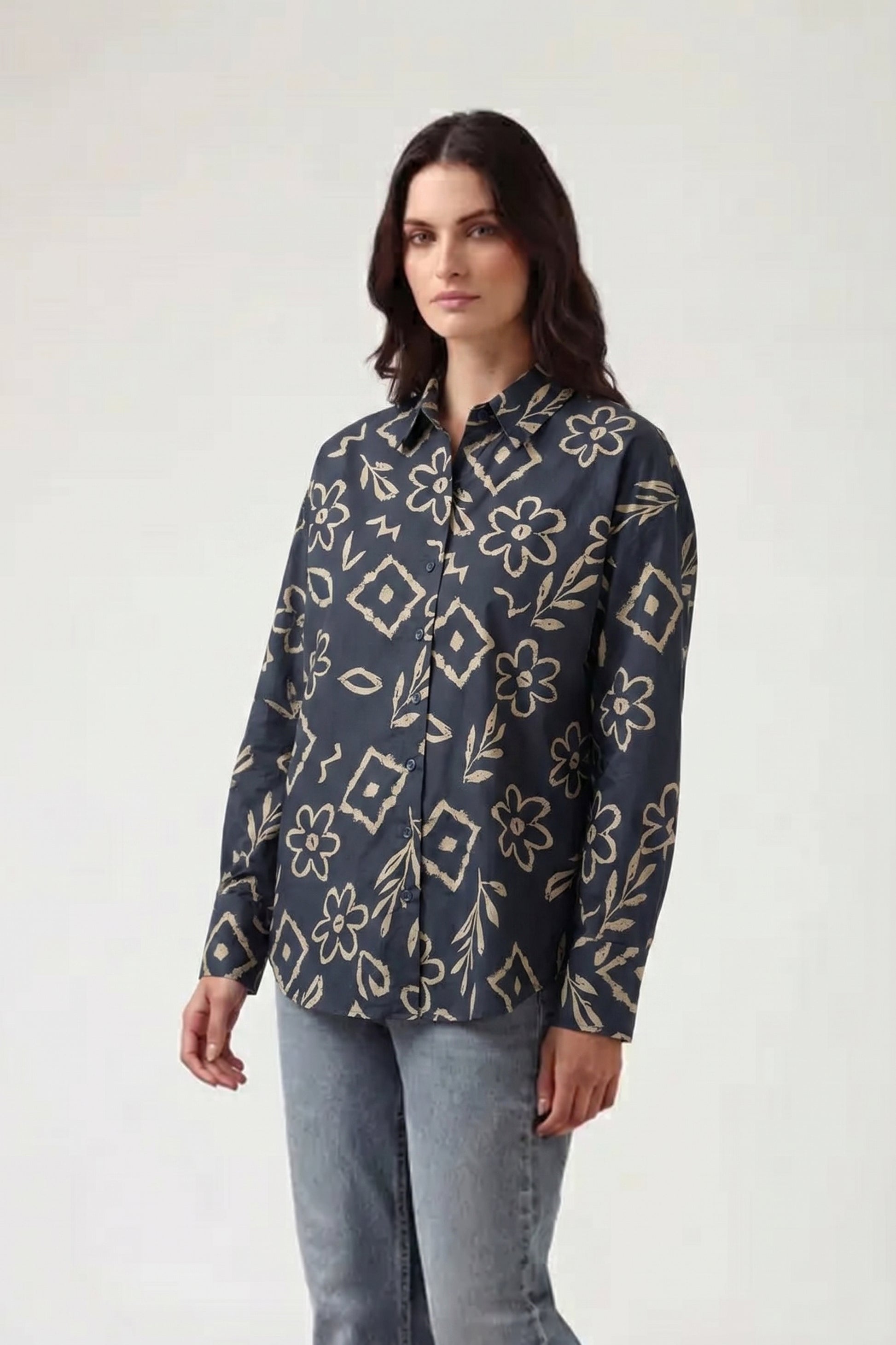 Woman wearing a dark floral patterned shirt on a white background