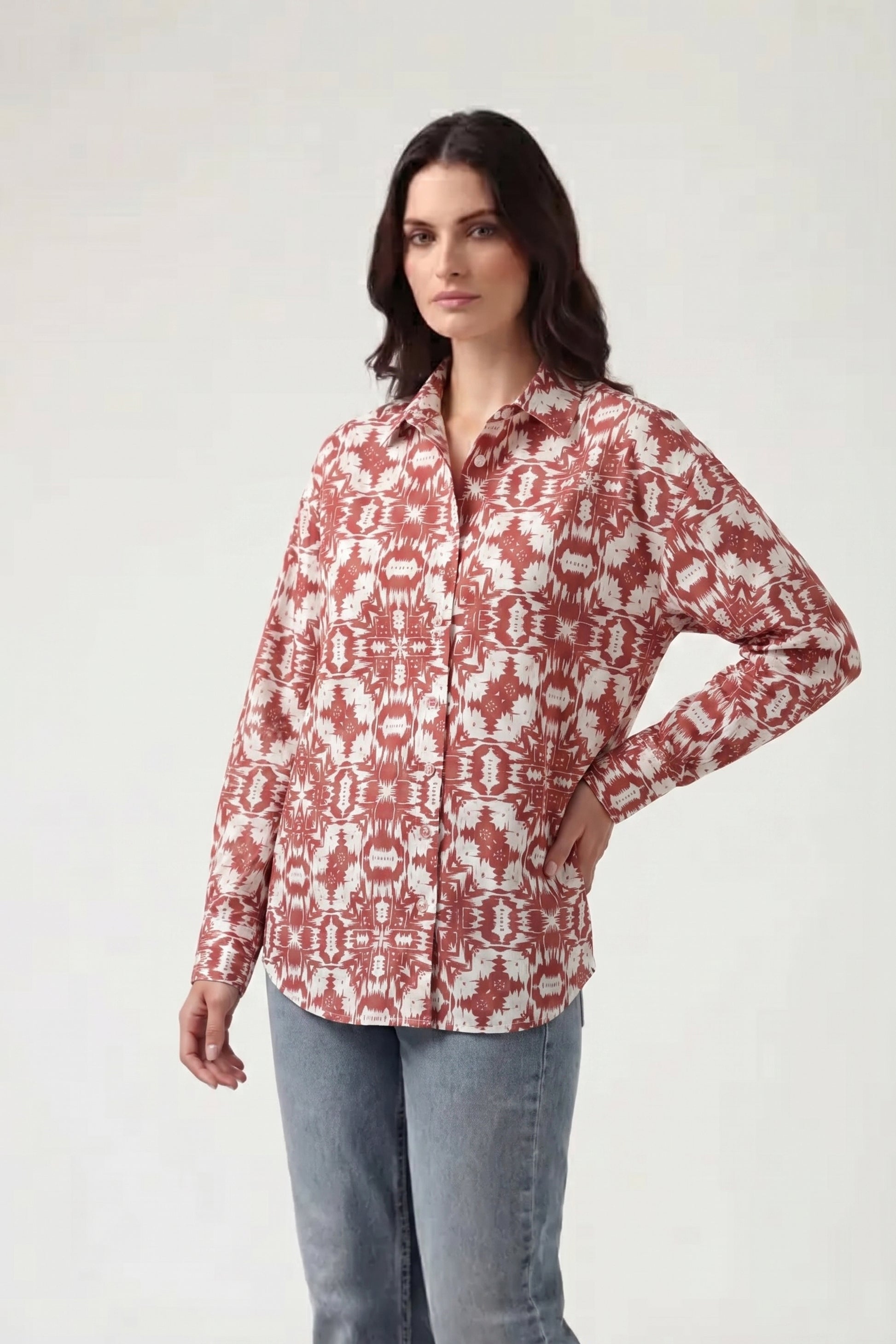 Woman wearing a red and white patterned shirt with light blue jeans on a white background