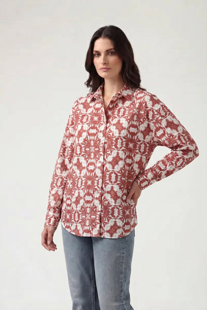 Woman wearing a red and white patterned shirt with light blue jeans on a white background