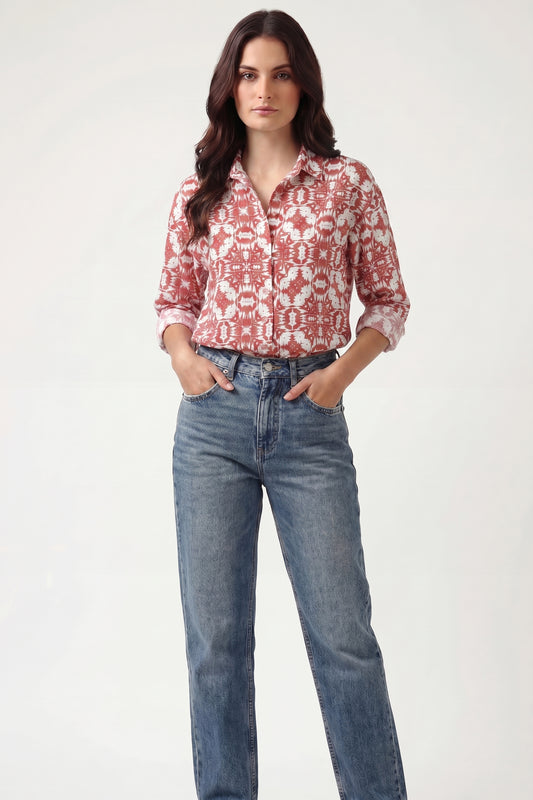 Woman wearing a red patterned blouse and blue jeans on a white background